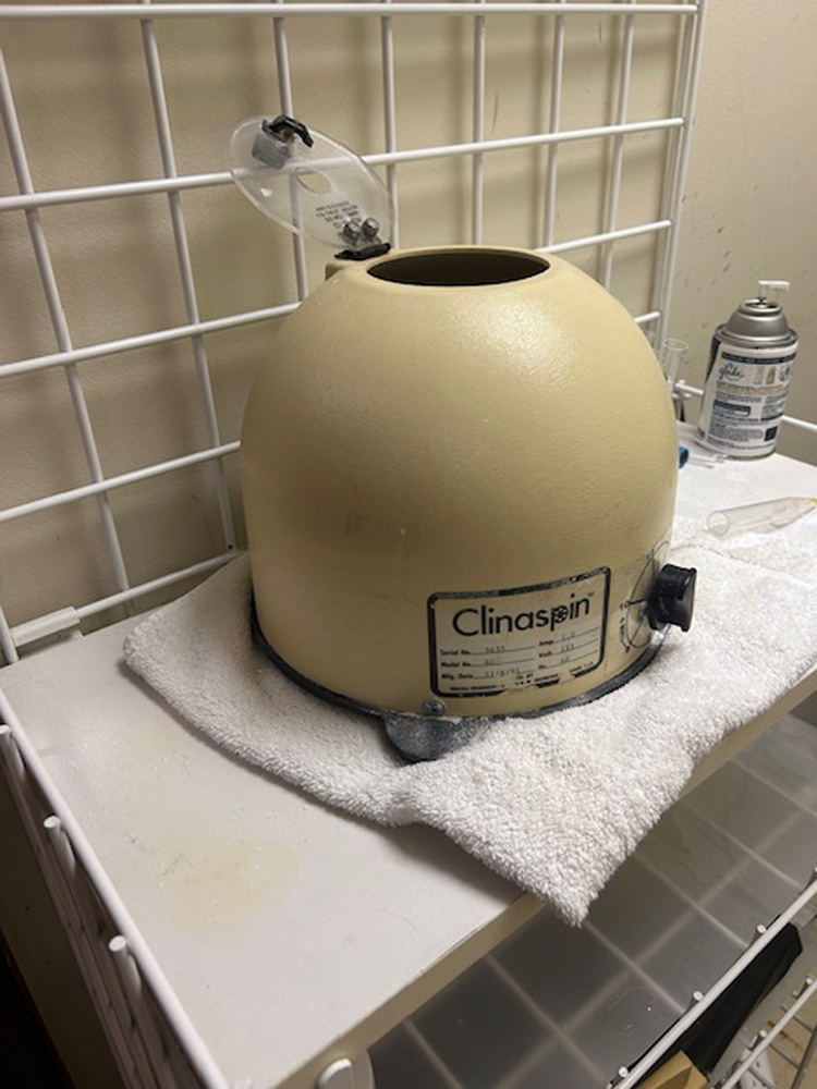 Beige dental centrifuge with open lid on a towel-covered cart in a lab setting